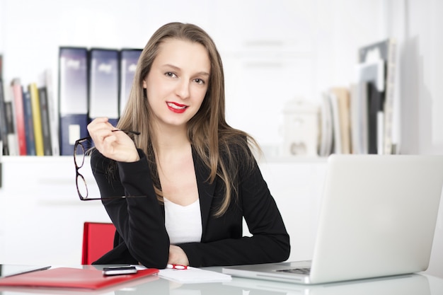 Businesswoman talking to mobile and working in office with laptop