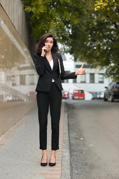 Businesswoman talking on the phone catches a taxi