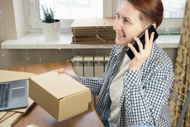 Photo businesswoman talking on the phone and holding a cardboard box in her hands