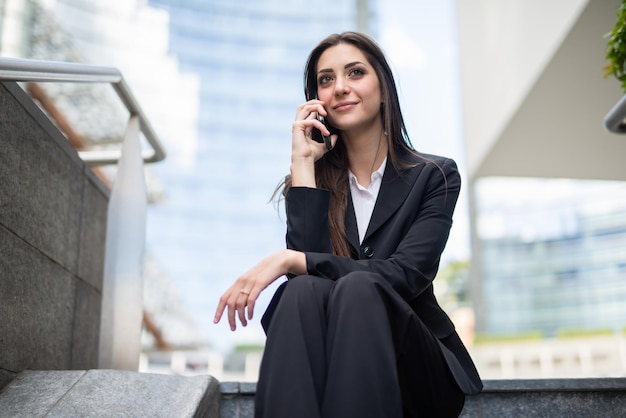 Imprenditrice parlando al telefono mentre è seduto su una scala