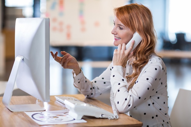 Donna di affari che parla sul telefono in ufficio