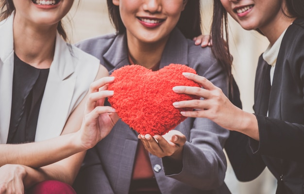 Photo businesswoman team giving a red heart to a customer