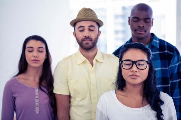 Businesswoman and team with eyes closed in creative office