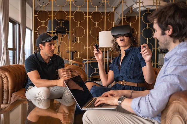 Businesswoman testing a new game on virtual reality simulator next to colleagues in the hall of an hotel