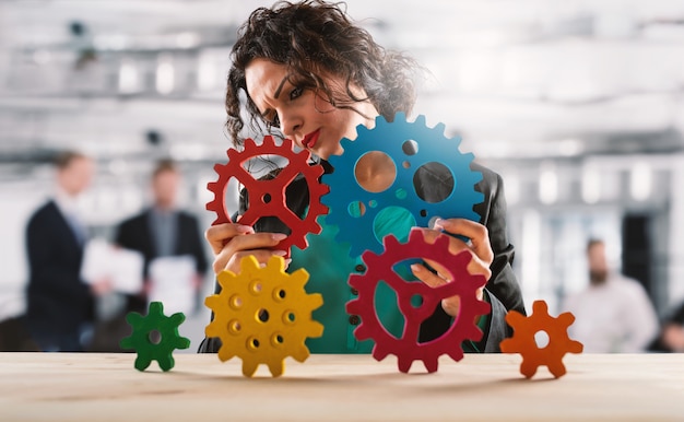 Foto la donna di affari prova a lavorare con gli ingranaggi. concetto di lavoro di squadra e collaborazione.