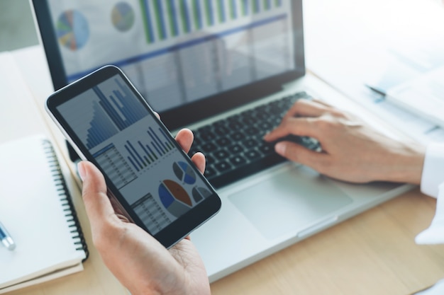 Businesswoman use computer and mobile phone to analyse online information.