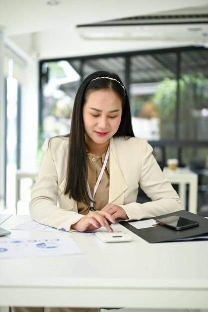 Photo a businesswoman using a calculator to recheck financial data and analyzing financial report
