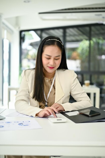 A businesswoman using a calculator to recheck financial data and analyzing financial report