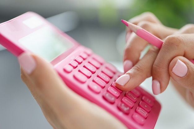 Businesswoman using calculator with pen in hand calculating financial expenses budgeting