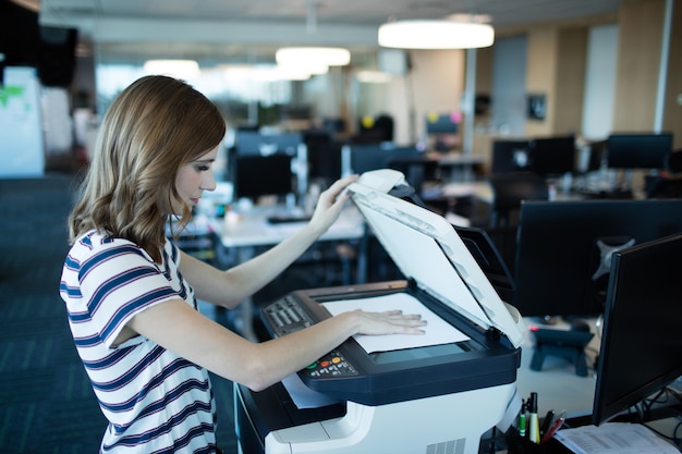 Деловая женщина, использующая копировальный аппарат в офисе