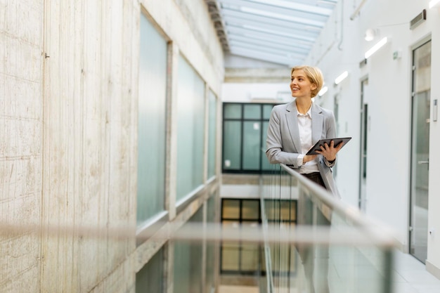 Businesswoman using digital tablet on modern office hallway