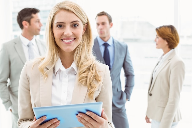 Businesswoman using digital tablet with colleagues behind