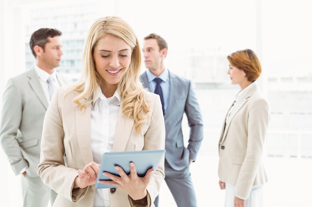 Businesswoman using digital tablet with colleagues behind