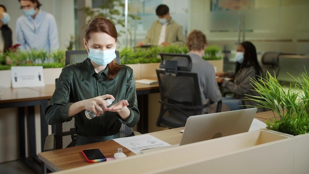 Donna d'affari che usa disinfettante per le mani in ufficio