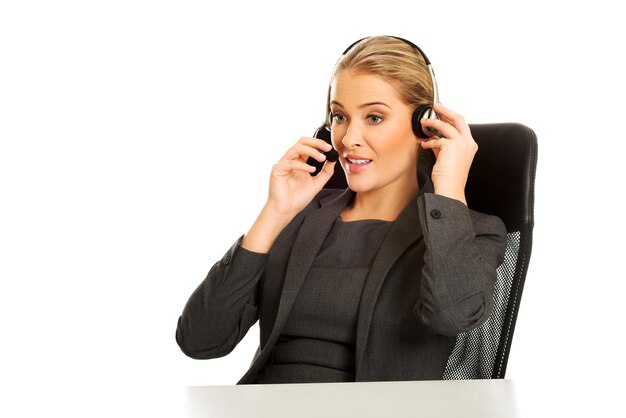 Photo businesswoman using headset while sitting on chair against white background