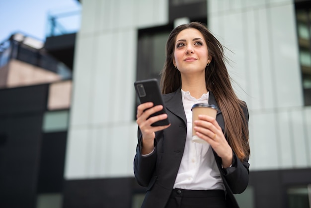 屋外を歩きながら彼女の携帯電話を使用して実業家