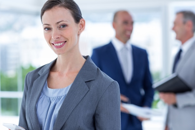 businesswoman using her phone with two colleague behind her 