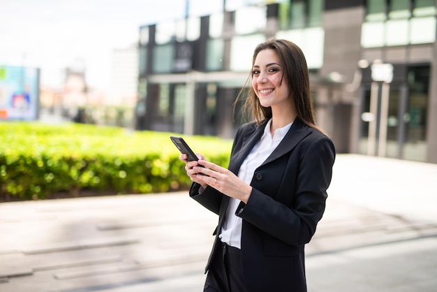 Imprenditrice utilizzando il suo smartphone in una piazza moderna della città