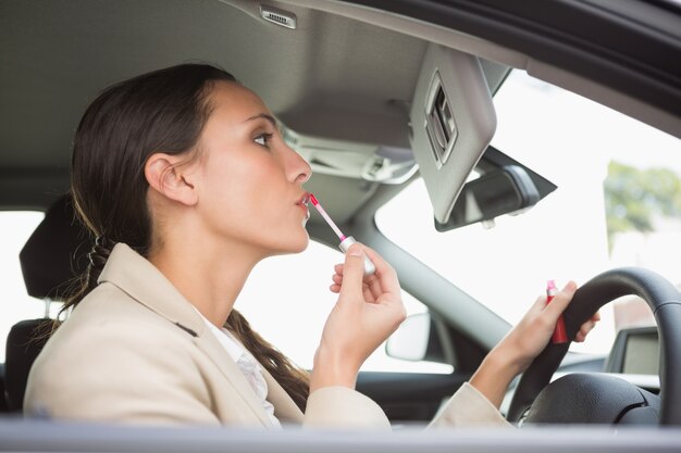 Photo businesswoman using mirror to put on lip gloss