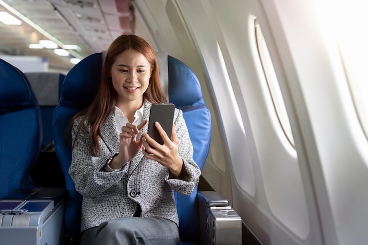 Photo 飛行機で携帯電話を使っているビジネスウーマン