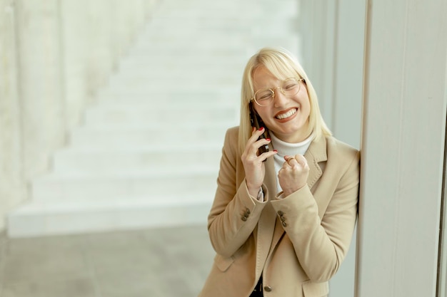 Businesswoman using mobile phone on modern office hallway