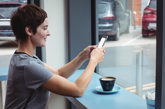 コーヒーを飲みながら携帯電話を使用して実業家