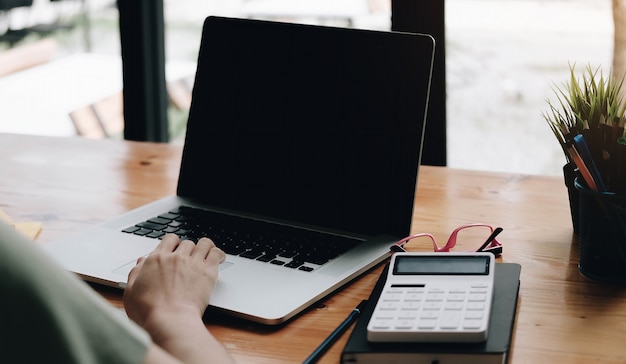 Businesswoman using mockup laptop while working with calculator for financial.