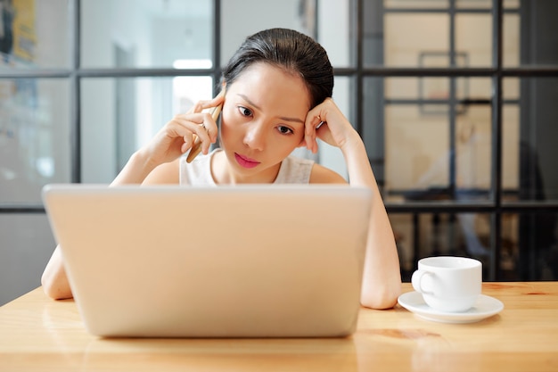 Businesswoman using phone and laptop in work