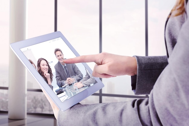 Businesswoman using a tablet pc against portrait of a positive team sitting at a table