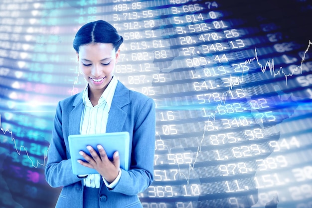 Businesswoman using a tablet with colleagues behind against stocks and shares