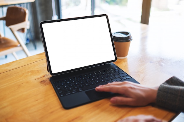  of a businesswoman using and touching on tablet touchpad with blank white desktop screen as computer pc with coffee cup on the table