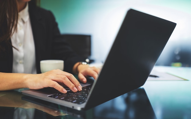 ラップトップコンピューターのキーボードを使用してオフィスで作業しながら入力する実業家