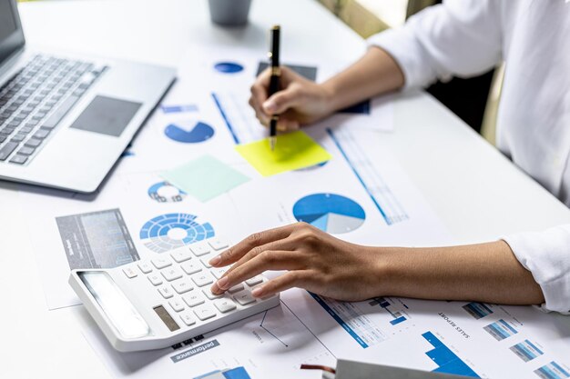 Photo businesswoman using a white calculator, a financial businessman examining the numerical data on a company financial document, she uses a calculator to verify the accuracy of numbers.