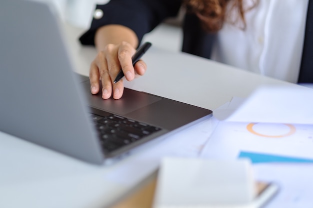 Donna d'affari che utilizza e lavora su un computer portatile e documenti in ufficio