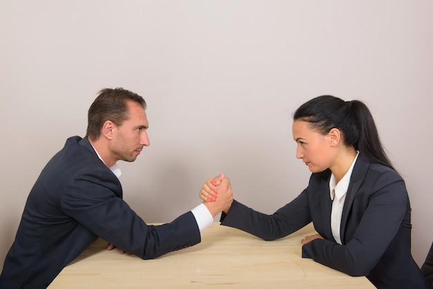 Businesswoman vs businessman arm wrestling on working table