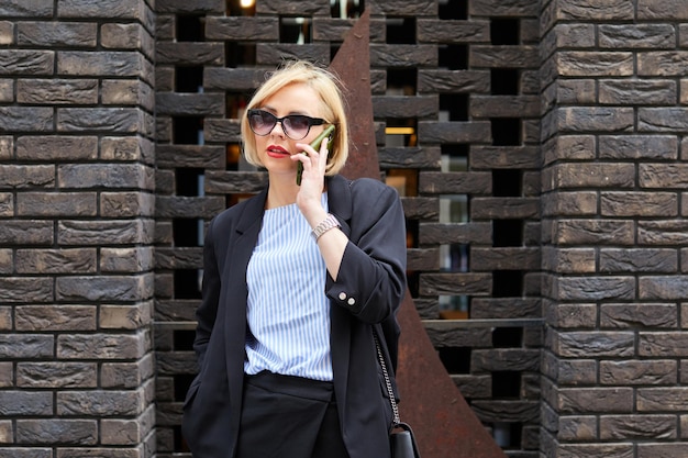 Photo businesswoman walking across the street talking on smart phone