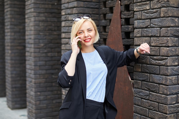 Businesswoman walking across the street talking on smart phone