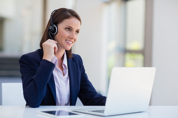 Businesswoman wearing headphone using laptop