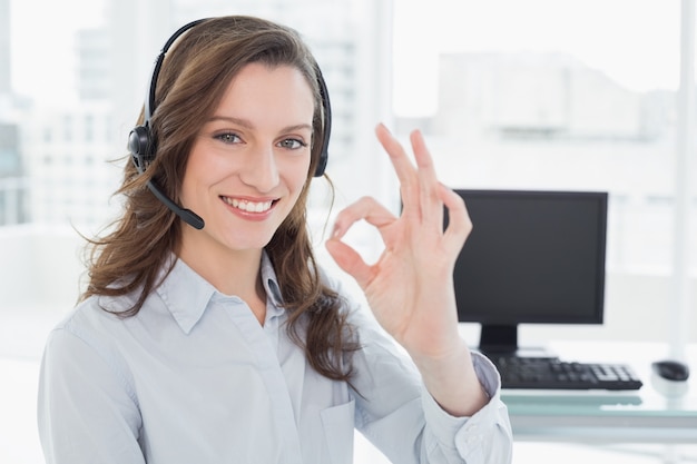 Foto la cuffia avricolare d'uso della donna di affari mentre gesturing bene firma dentro l'ufficio