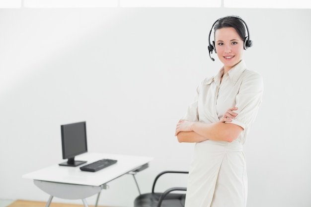 Businesswoman wearing headset with arms crossed in office