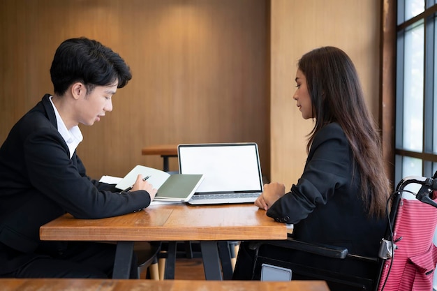 Businesswoman in wheelchair talking with business partner in modern office