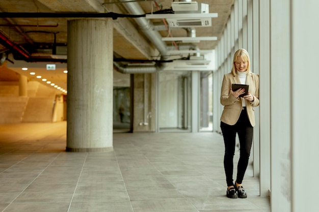 Businesswoman with digital tablet on modern office hallway