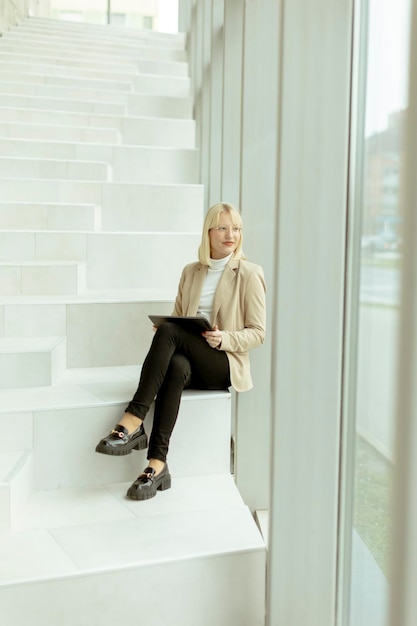 Businesswoman with digital tablet on modern office stairs