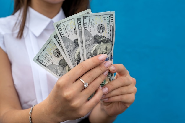 Businesswoman with dollars isolated on blue. Finance concept