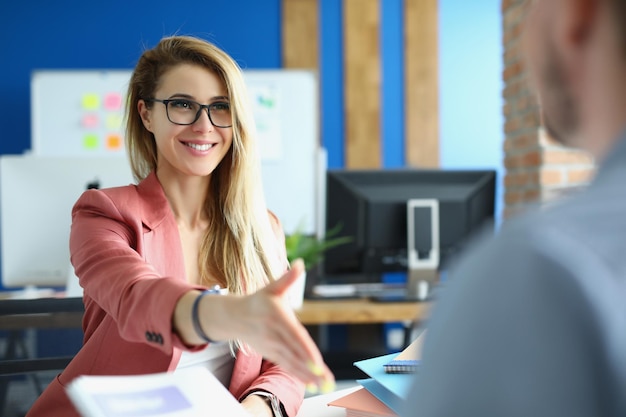 Businesswoman with glasses giving her hand for handshake to her partner