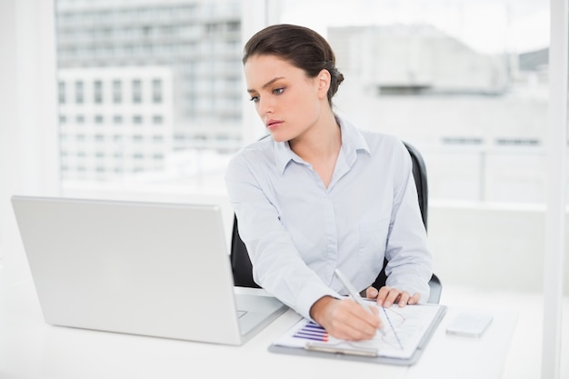 Businesswoman with graphs and laptop in office