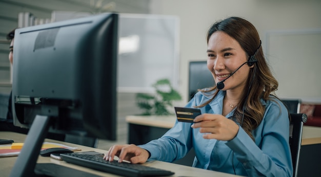 Businesswoman with headset using computer and credit card