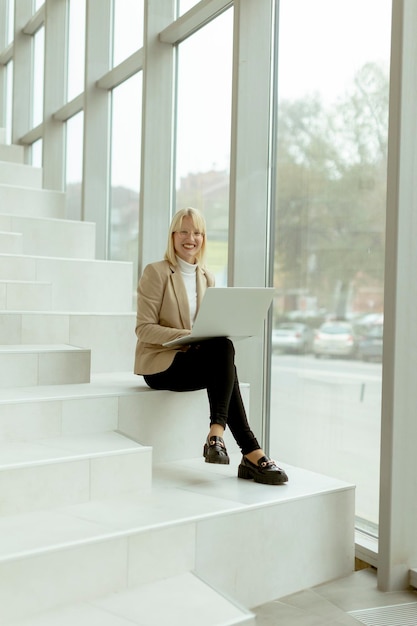 Businesswoman with laptop on modern office stairs