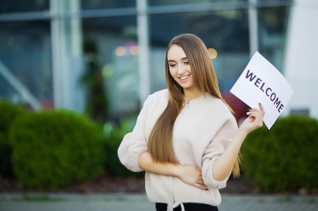 Businesswoman with long Hair Holding a sign Board with a Welcome has Airport Background