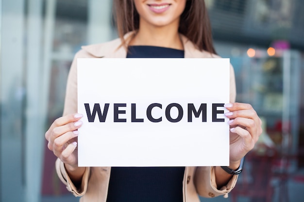 Photo businesswoman with long hair holding a sign board with a welcome has airport